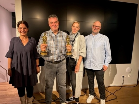 Die Mitarbeiter der Film Commission Stuttgart stehen neben Gerd Nefzer mit seinen beiden Oscars für ein Foto